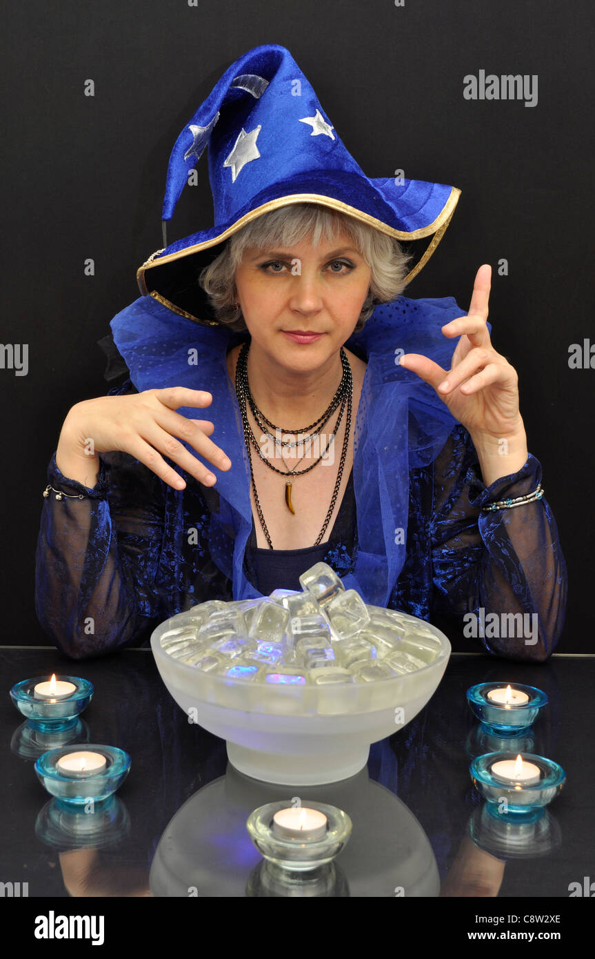 Hellseher in blauen Hut mit magischen Kristallen auf schwarzem Hintergrund Stockfoto