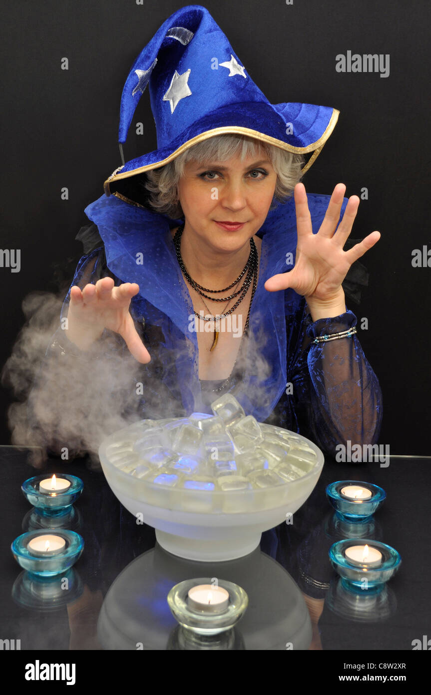 Hellseher in blauen Hut mit magischen Kristallen auf schwarzem Hintergrund Stockfoto