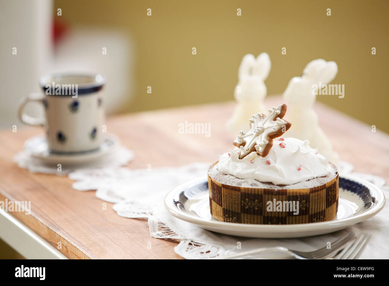 Kaninchen-Form beleuchtete Kerze, Tasse und dekorative Kuchen auf Schreibtisch Stockfoto