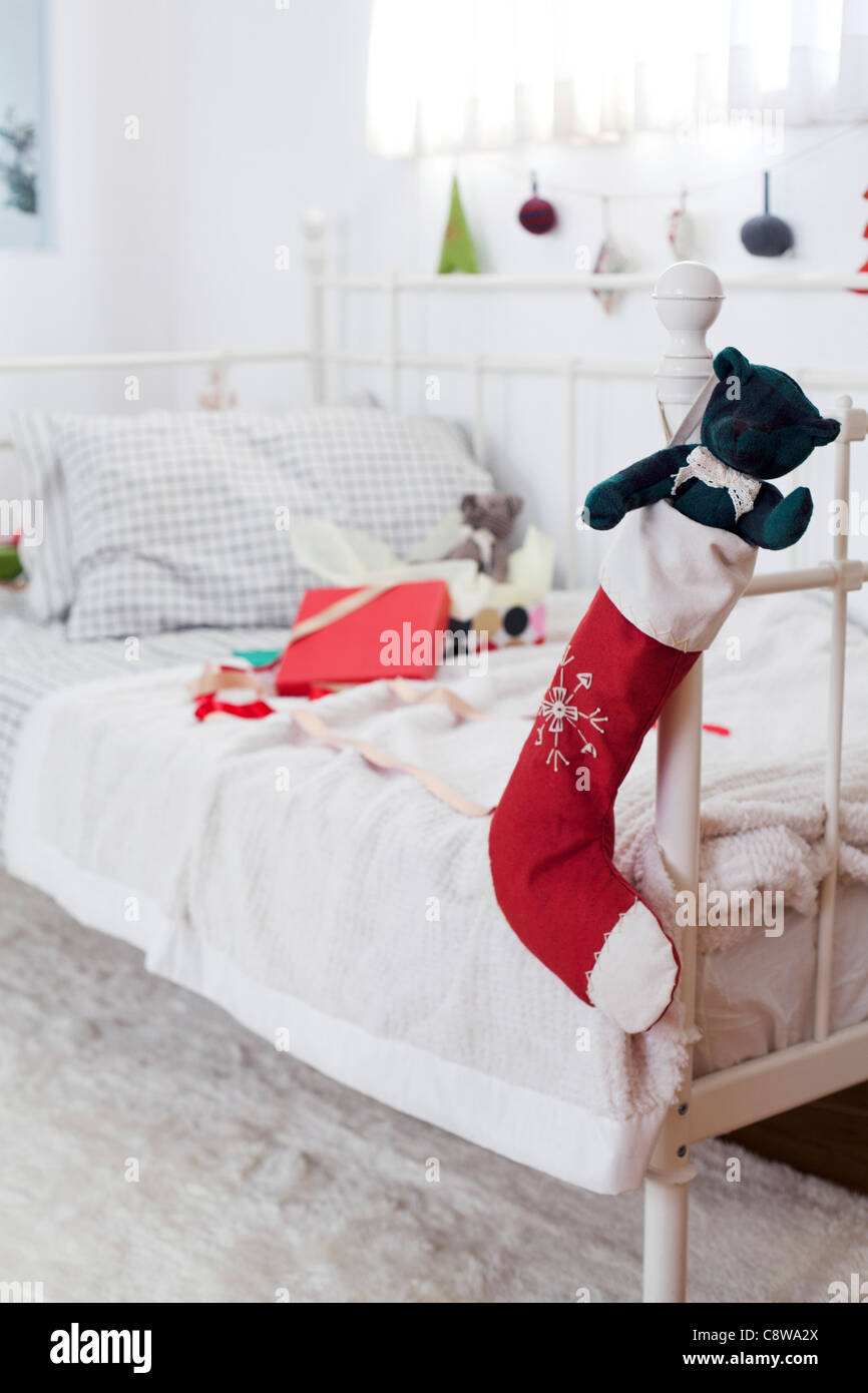 Teddybär In Weihnachtsstrümpfe Couch Griff hängen und Geschenk ausgepackt Stockfoto