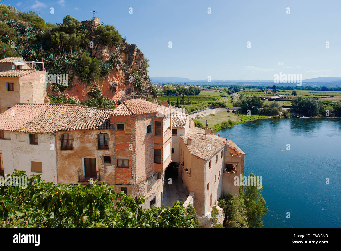 Erhöhter Blick auf alte Steinhäuser, die am Ufer des Ebro-Flusses stehen. Miravet Dorf, Katalonien, Spanien. Stockfoto