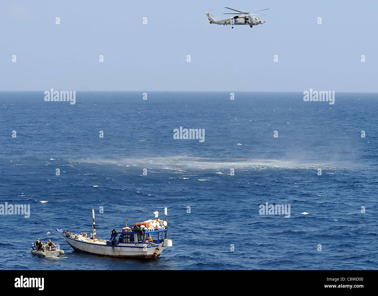 Vella Gulf (CG-72) mithilfe ein steif-geschältes aufblasbares Boot nähern sich eine Dhau, die Hilfe benötigen. Stockfoto