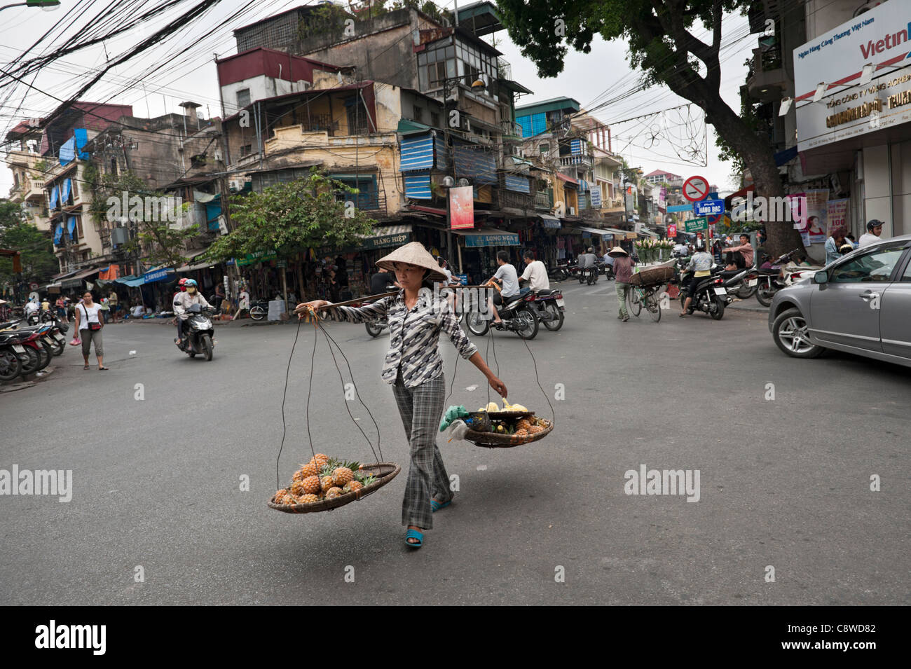 Hanoi Straße Verkäufer trägt ein traditionelles 'Quang Ganh' Schulter tragen Gerätes, Verkauf von Ananas. Vietnam Stockfoto