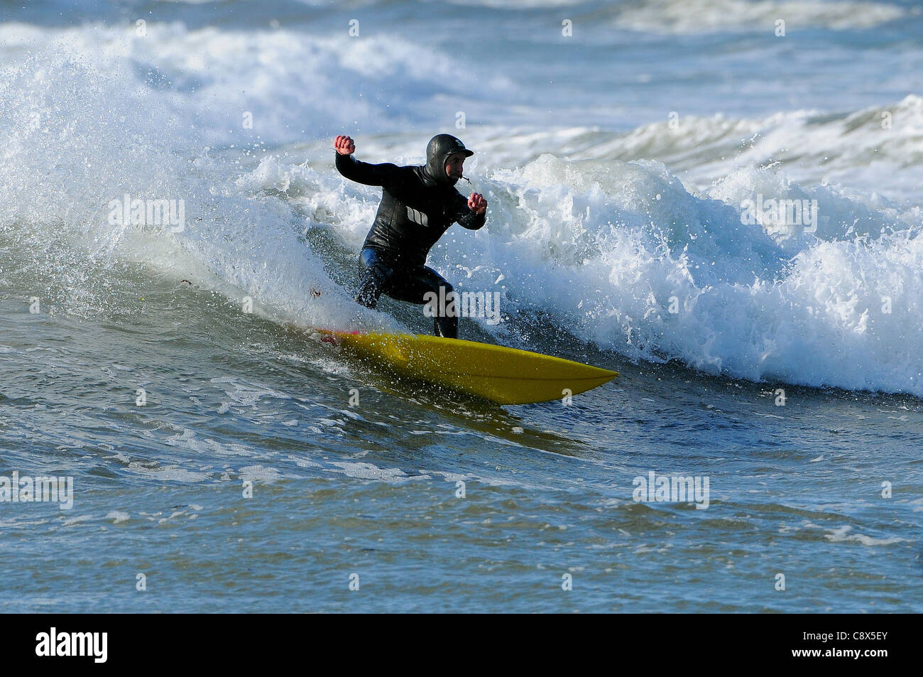 Eine Surfer reitet eine Welle Größe Strand in Devon im November. Stockfoto