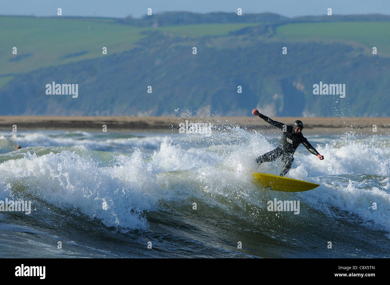 Eine Surfer reitet eine Welle Größe Strand in Devon im November. Stockfoto