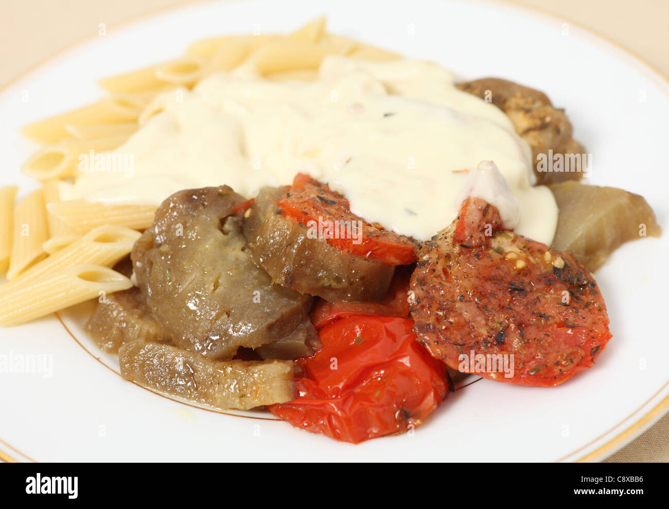 Eine Mahlzeit mit gebackenen Tomaten und Aubergine (Aubergine) mit Penne-Nudeln serviert und gekrönt mit einem Käse-Sauce. Stockfoto