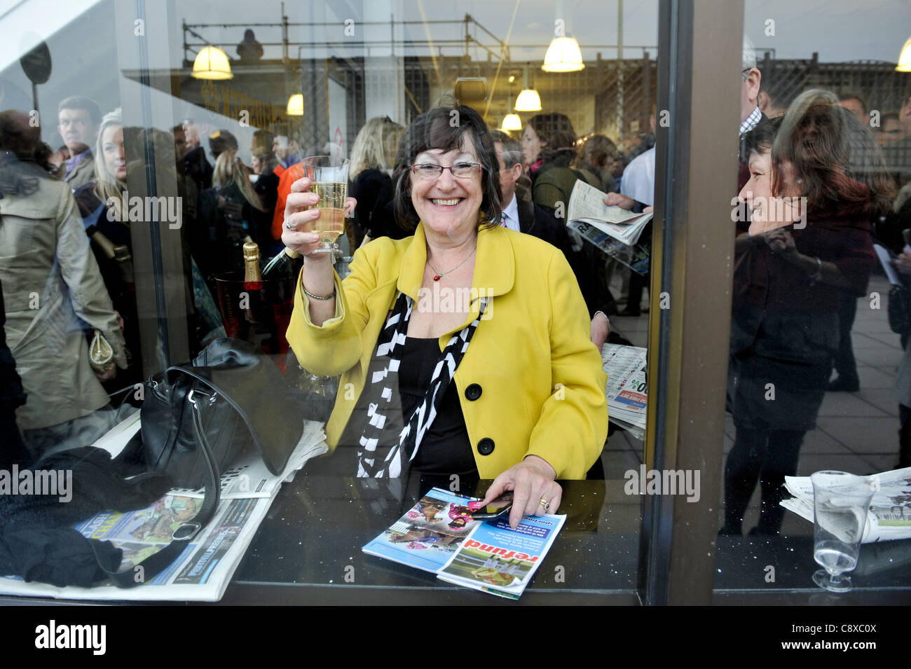 Ein Frau Punter feiert hält ein Glas Champagner nach eine gewonnene Wette bei Pferderennen in Cheltenham am Ladies Day. Stockfoto