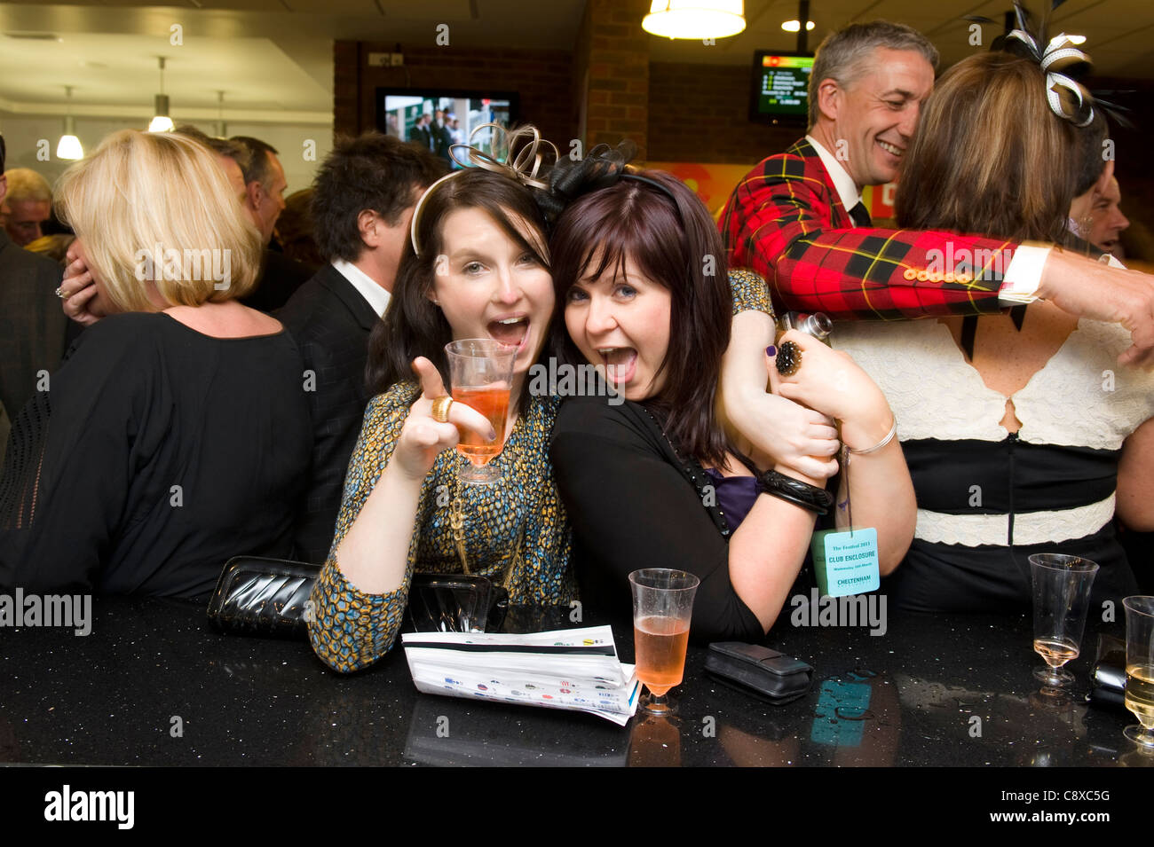 Zwei Freundinnen feiern mit Champagner nach eine gewonnene Wette mit auf einem Pferd bei Cheltentem Pferderennen. Stockfoto