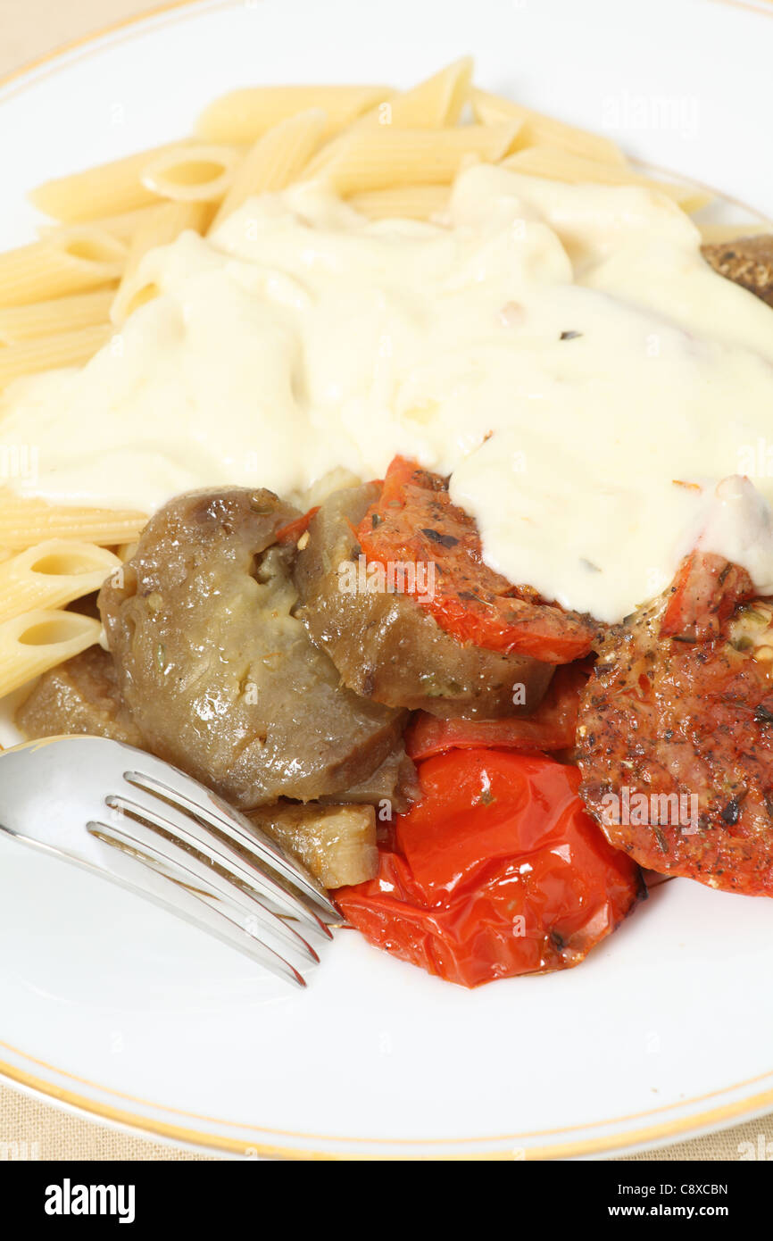 Eine Mahlzeit mit gebackenen Tomaten und Aubergine (Aubergine) mit Penne-Nudeln serviert und gekrönt mit einem Käse-Sauce. Stockfoto