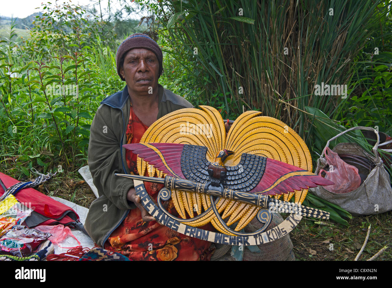 Lady verkaufen Holz geschnitzt Plaque zeigt Design des Staatswappen der Anzeige Paradiesvogel Papua New Guinea Stockfoto