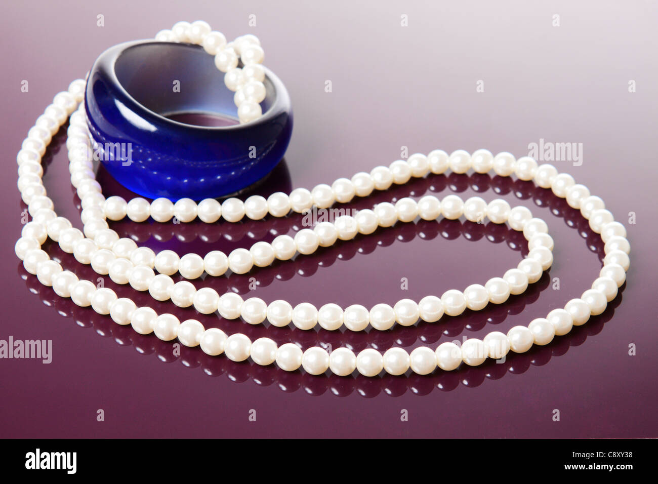 Perlenkette und blauen Armband über glänzende lila Hintergrund Stockfoto