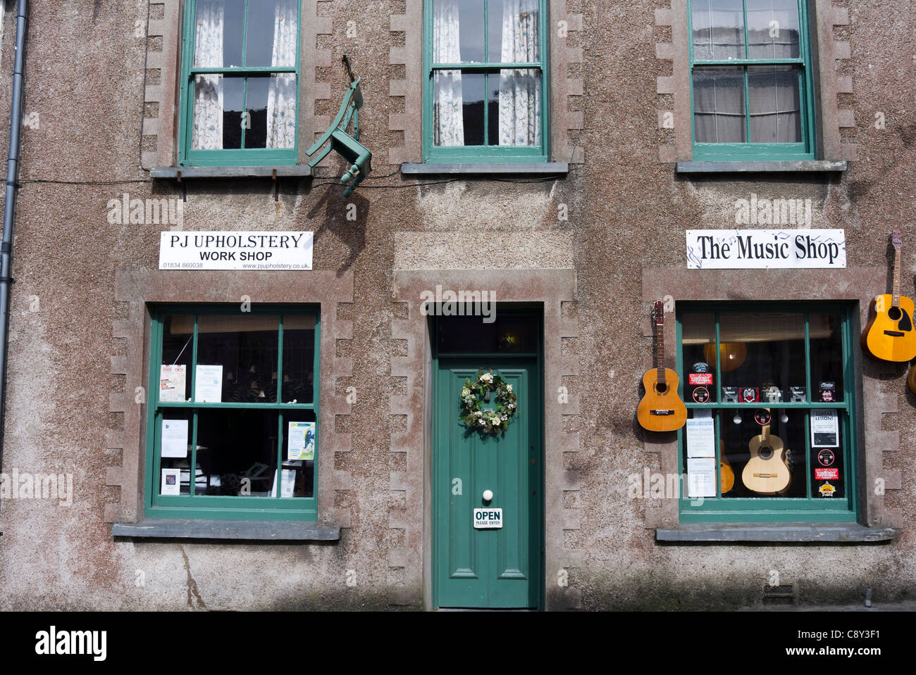 Gitarren und Stühle hängt an der Wand außerhalb der Musik und der Polsterung Geschäfte in Narberth, Pembrokeshire, Wales Stockfoto