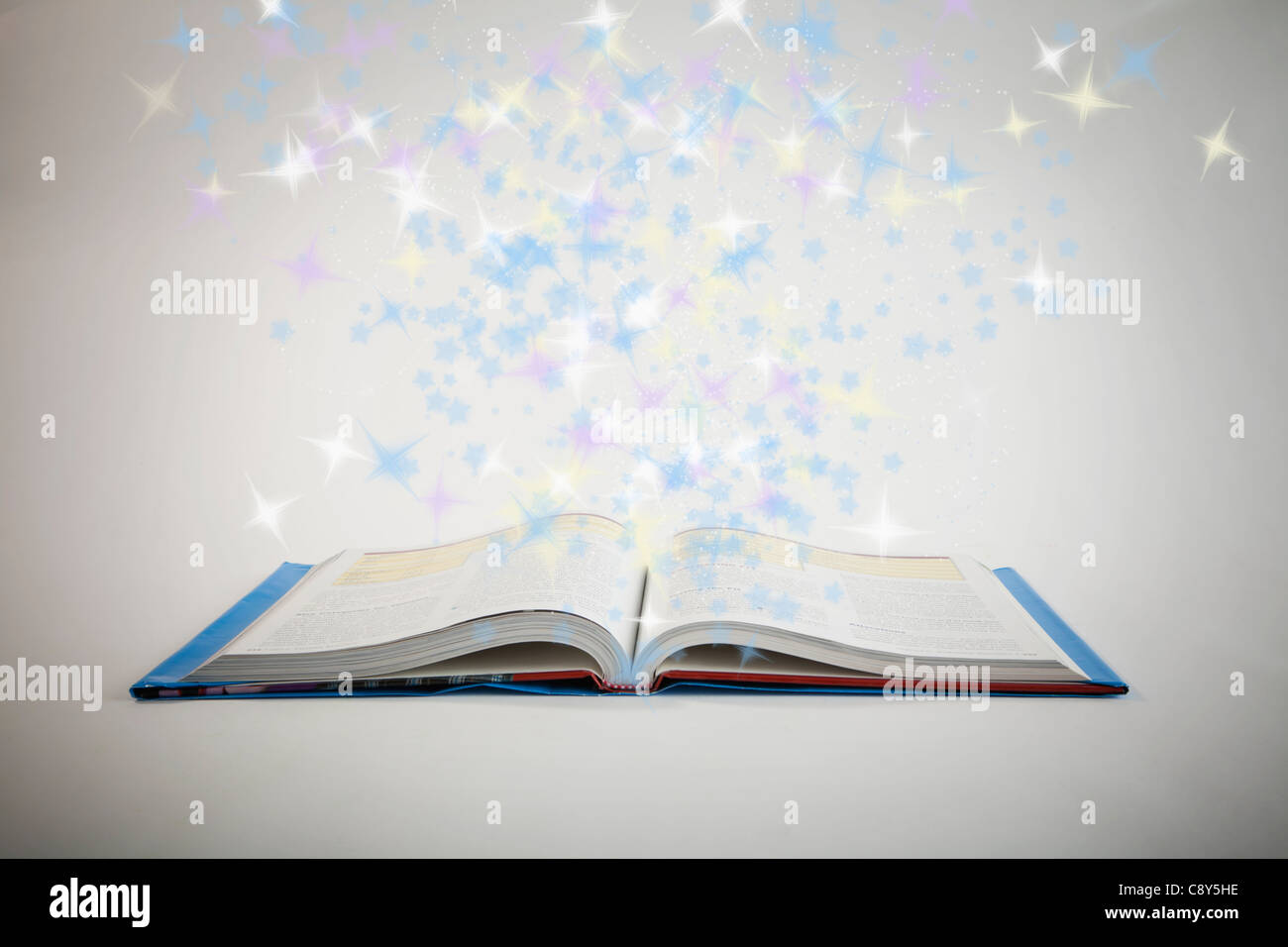 Glänzende Sterne fliegen über offenes Buch Stockfoto
