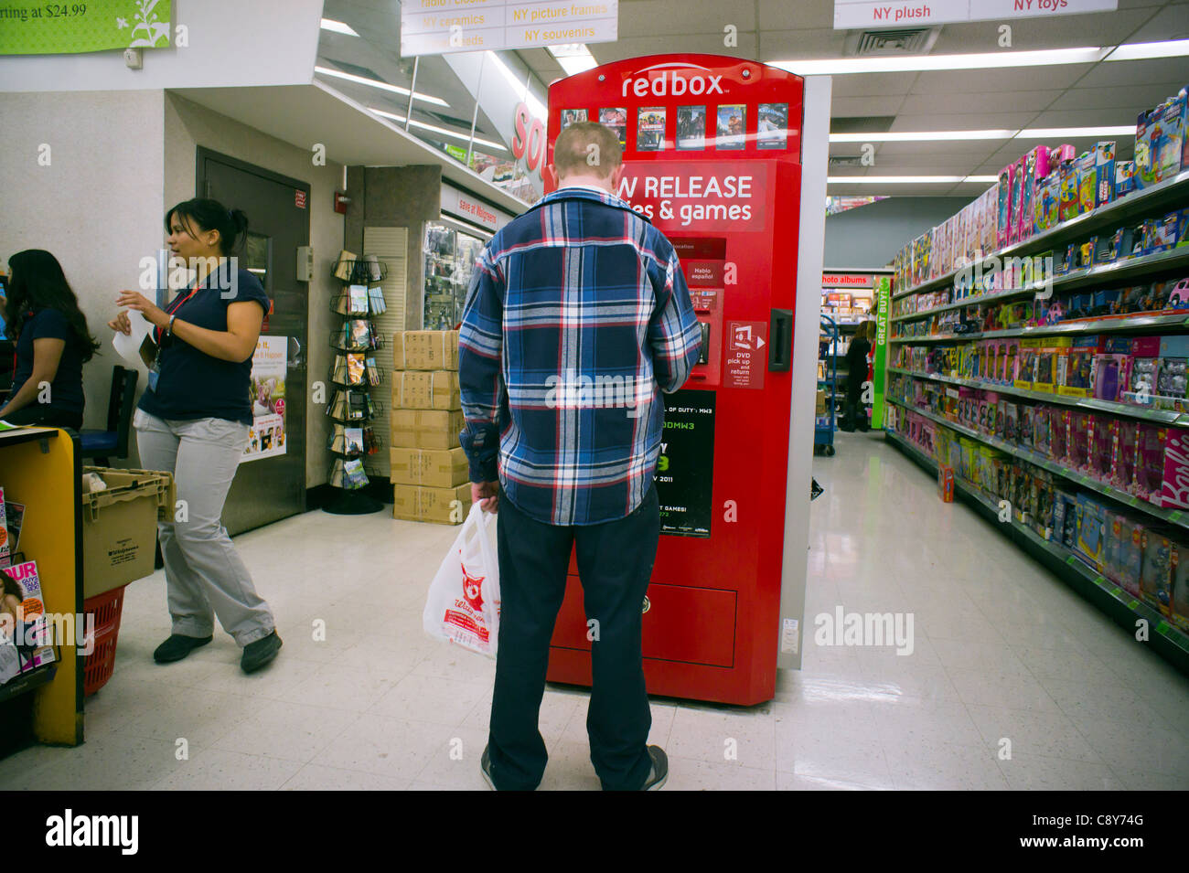 Ein Kunde nutzt eine Redbox Videoverleih Selbstbedienungskiosk, gesehen in einem Walgreen Drogerie in New York Stockfoto