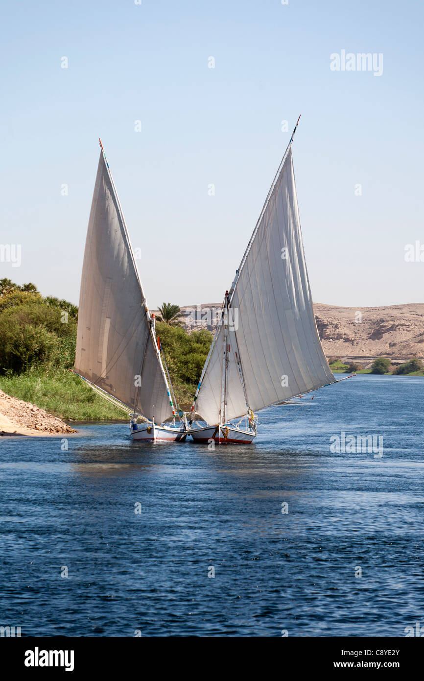 Zwei Nil Fellucas Segeln, Kamera im Tandem eine gebunden, andererseits Rundung eine Biegung des Flusses mit Bergen im Hintergrund Stockfoto