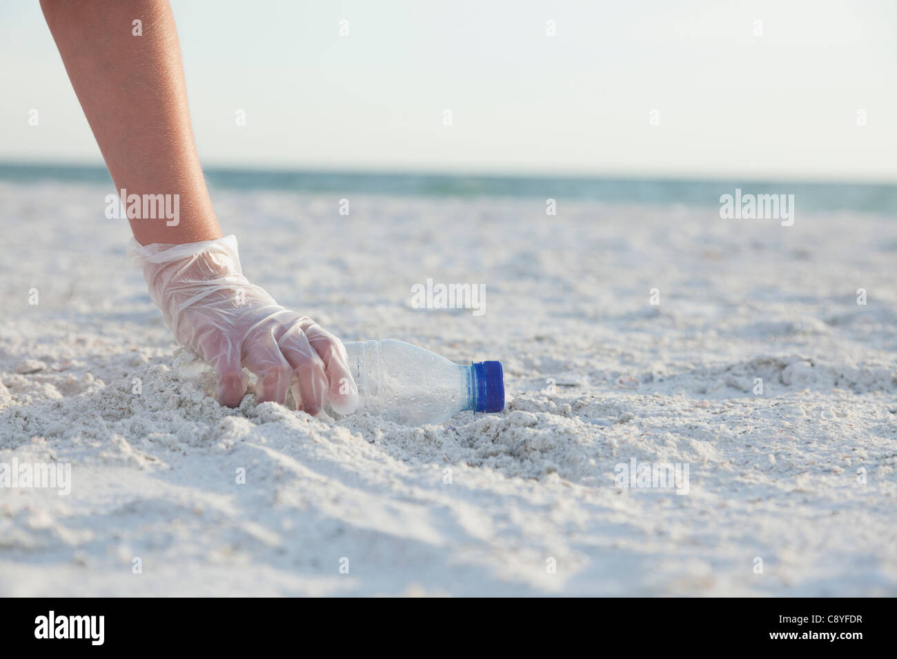 USA, Florida, St.Petersburg, Mädchen (10-11) Reinigung Strand, close-up der behandschuhten Hand Griff nach Kunststoff-Flasche Stockfoto