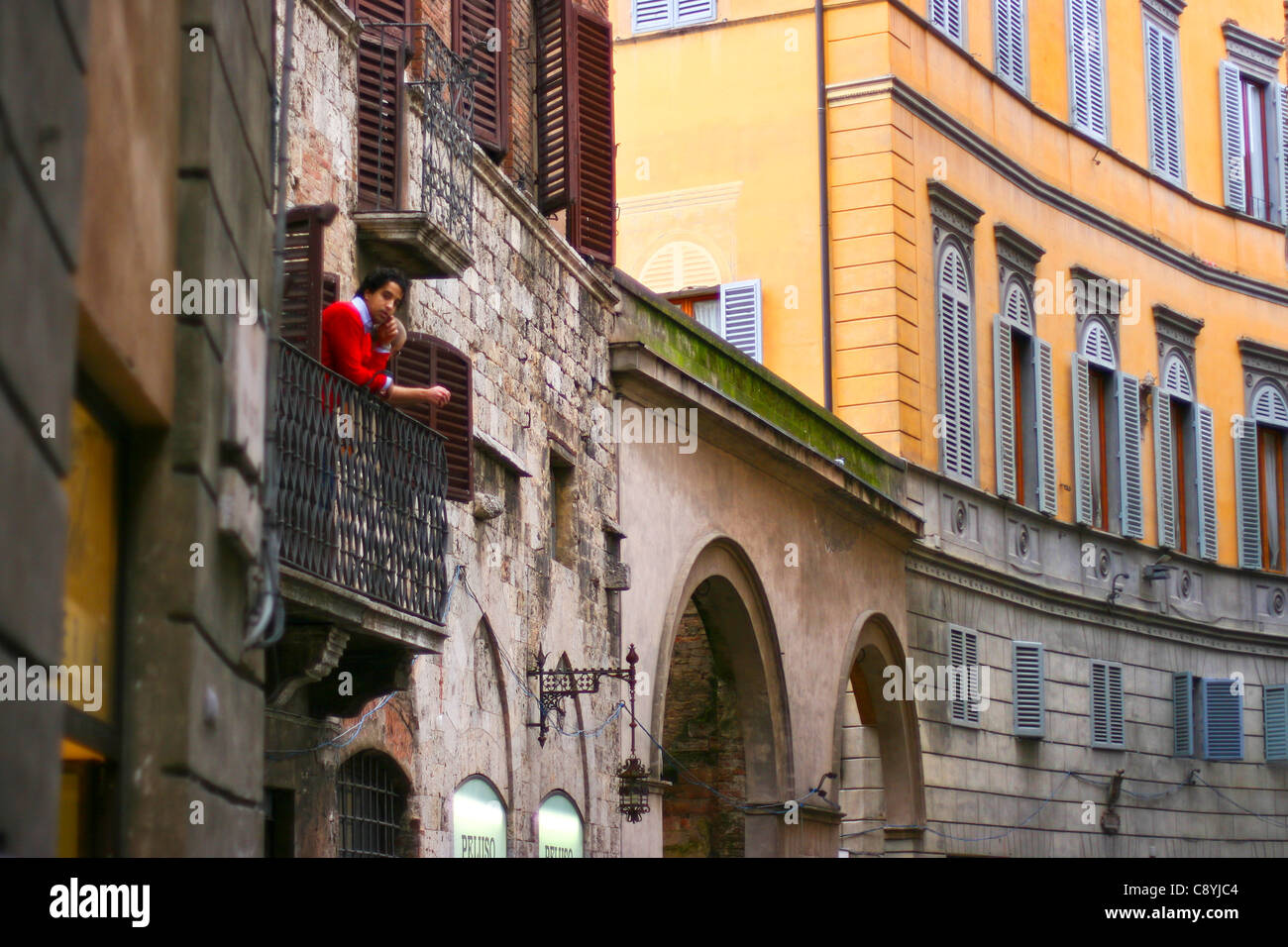 Junger Mann auf dem Balkon mit Blick auf die mittelalterliche Stadt Siena, Toskana Italien Stockfoto