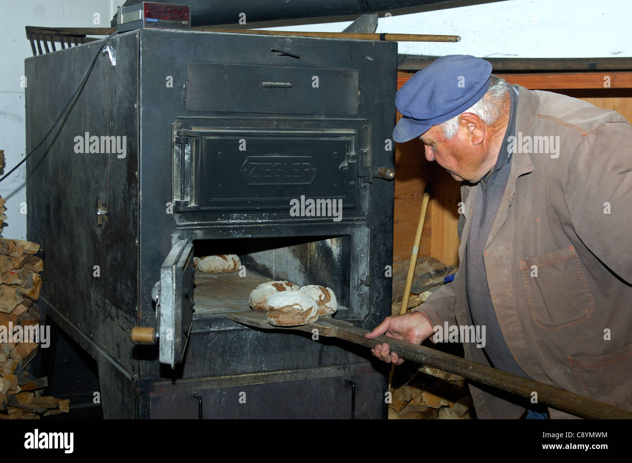 Baker, die Aufnahme von frisch gebackenen Walliser Roggen Brot aus dem Backofen der Dorfbäckerei in Erschmatt, Wallis, Schweiz Stockfoto