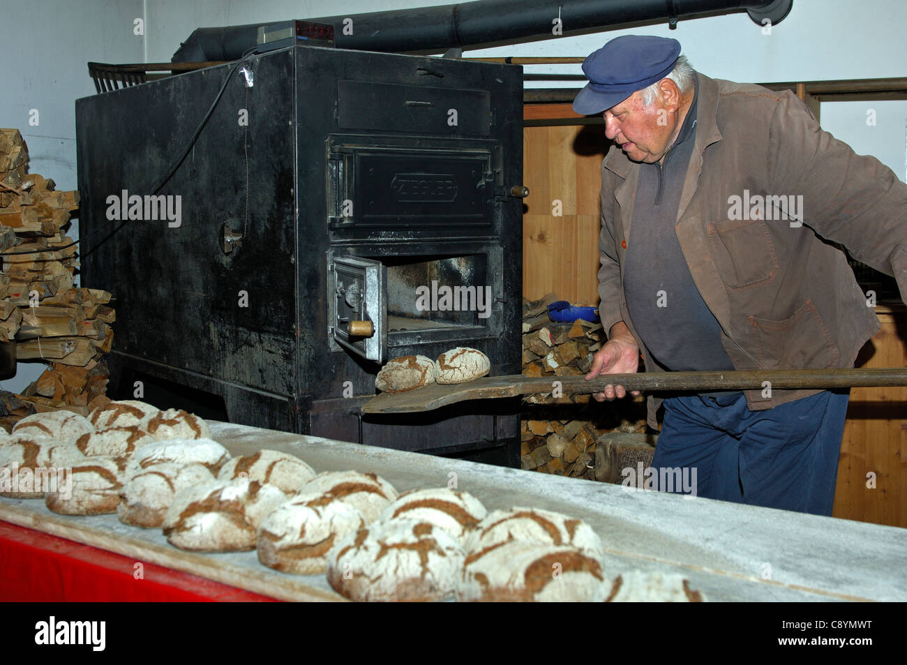 Baker, die Aufnahme von frisch gebackenen Walliser Roggen Brot aus dem Backofen der Dorfbäckerei in Erschmatt, Wallis, Schweiz Stockfoto