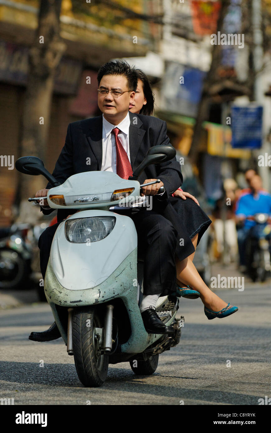 Asien, Vietnam, Hanoi. Hanoi Altstadt. Elegant gekleidet Vietnamesisch Paar Reiten auf einem Motorrad durch Hanoi... Stockfoto