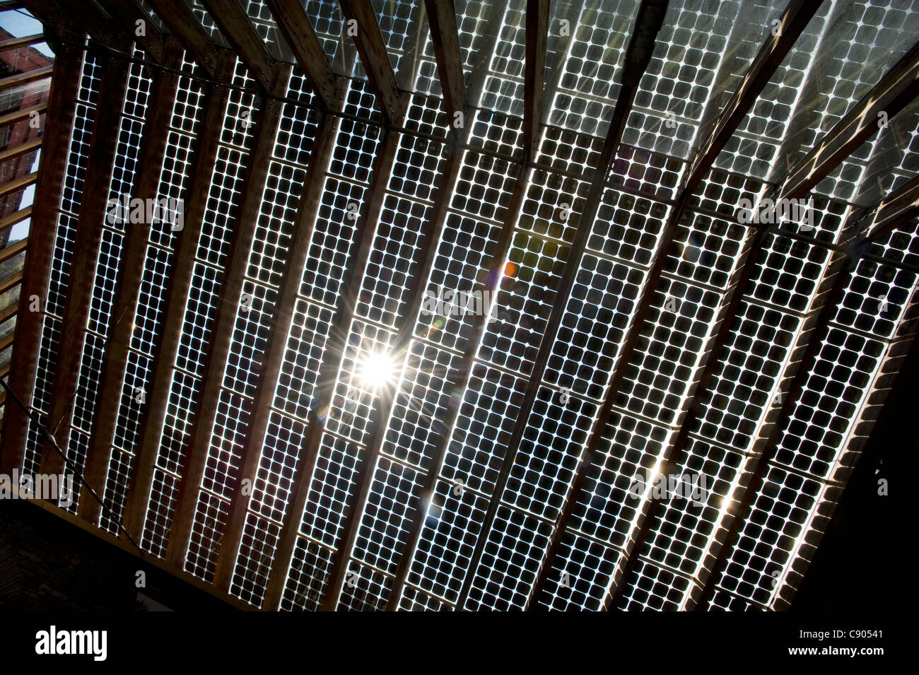 Die Sonne bricht durch das Innere der Solar Panals installiert auf dem Dach eines Gebäudes in der Mitte für Alternative Technologie, oder CAT, Europas führende Öko-Zentrum in Powys, Wales. Stockfoto