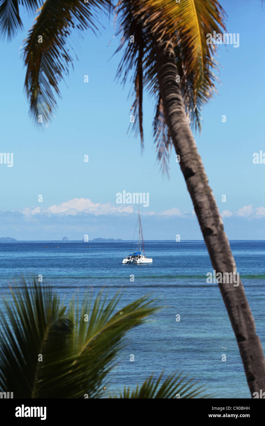 Ein Katamaran Segelboot verankert vor Ambatoloaka Strand, Nosy Be, Madagaskar, über Türkis klarem Wasser Stockfoto