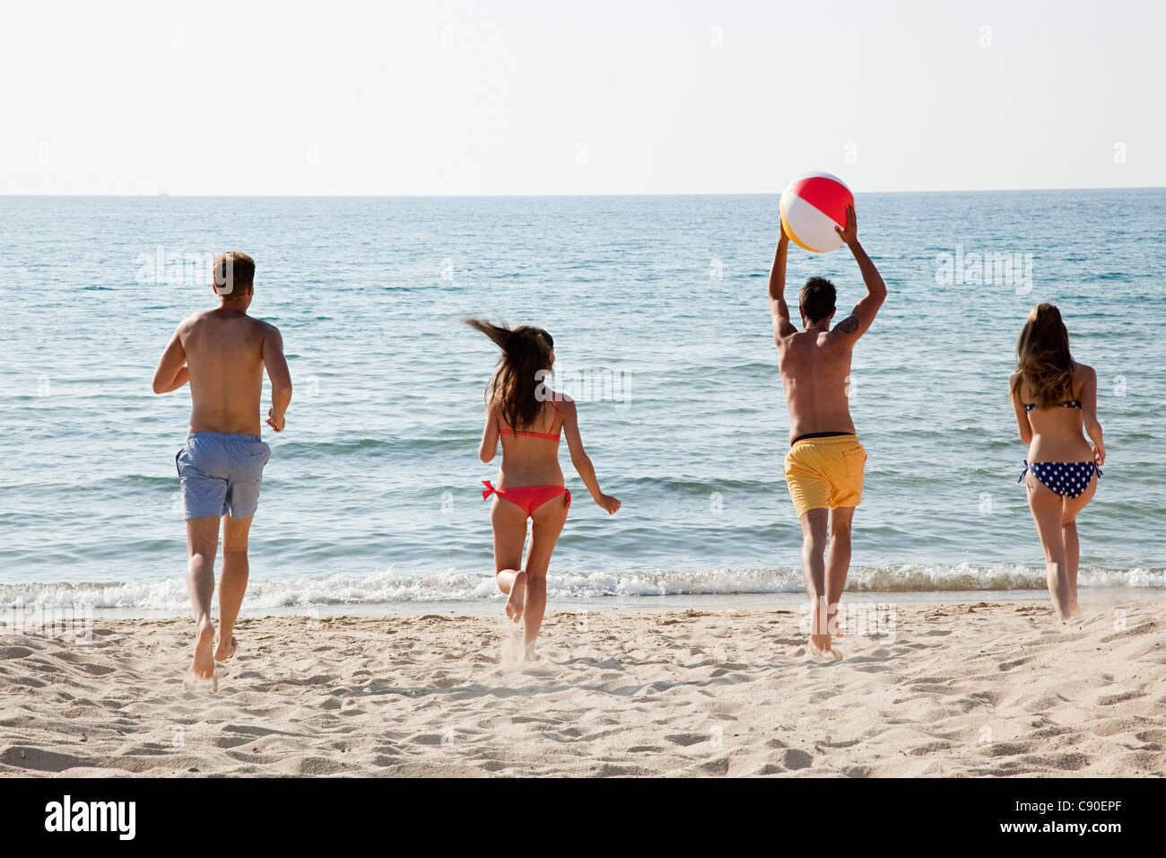 Vier Personen am Strand mit Beach-Ball spielen Stockfoto