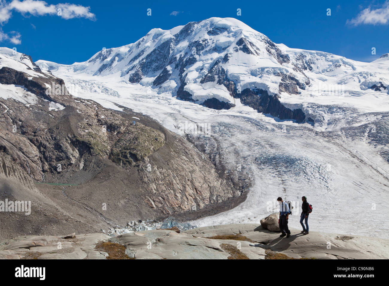 Zwei Wanderer in der Nähe von Grenz Gletscher Weg nach Monte-Rosa-Hütte-Liskamm im Hintergrund Zermatt Wallis Schweiz Myclimate audio t Stockfoto
