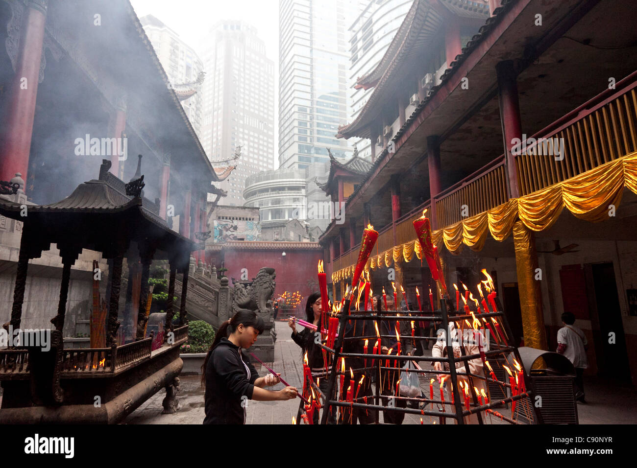 Frauen, die eine rote Beleuchtung Kerze buddhistische rituelle Luohan Tempel Wohn Builidngs und Apartments im Hintergrund Chongqing Peopl Stockfoto