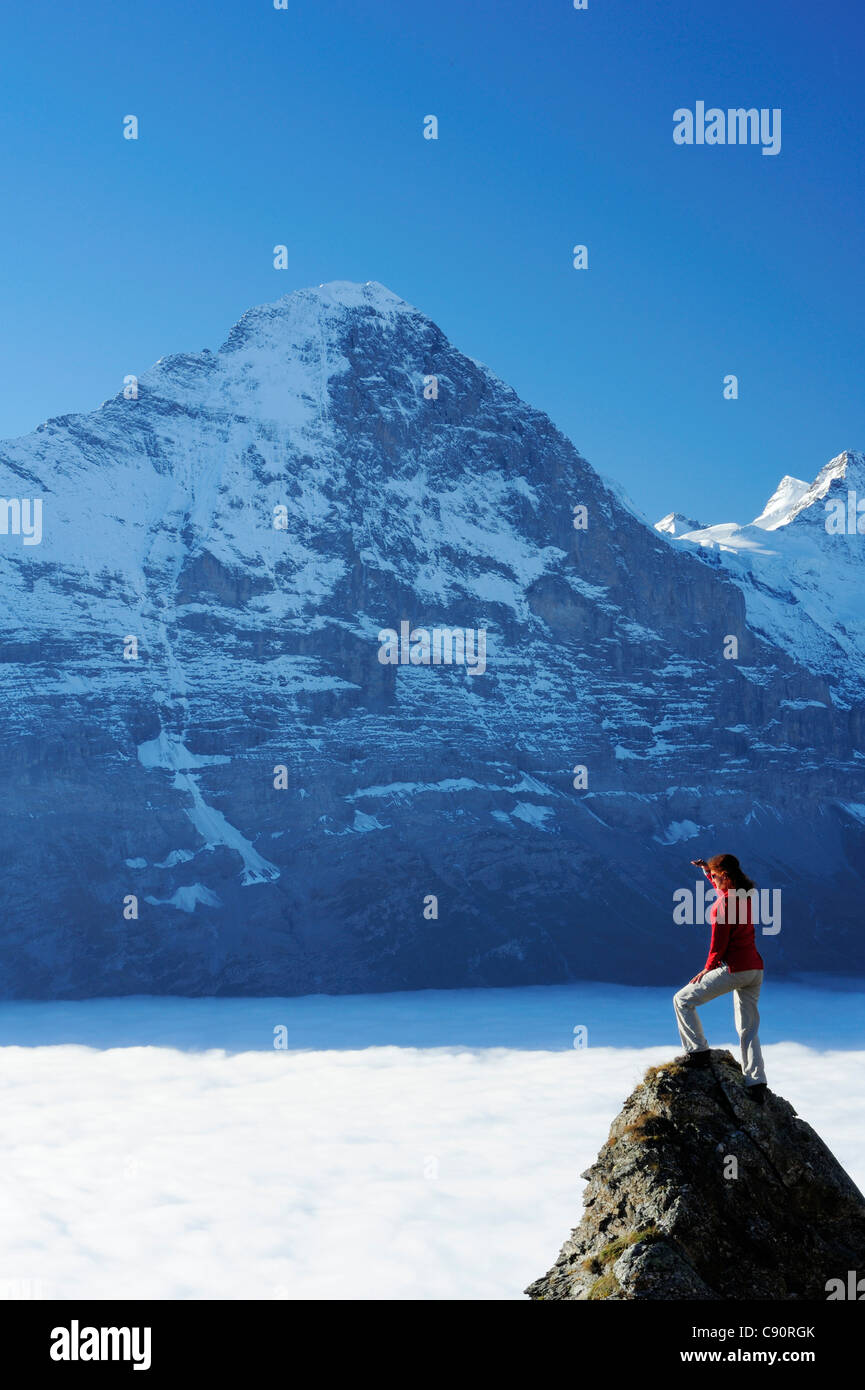 Frau stehend auf Felsen und mit Blick auf Eiger Nordwand über dem Nebelmeer, Bussalp, Grindelwald, UNESCO World Heritage sitzen Stockfoto