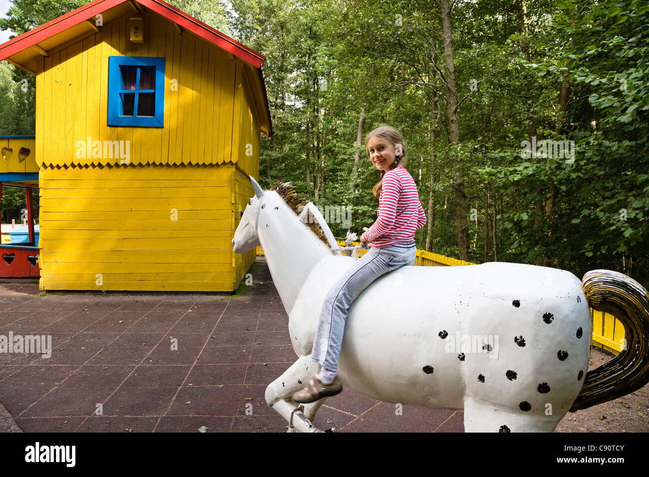 Mädchen sitzen auf einem hölzernen Pferd, Astrid Lindgren Vaerld, Astrid Lindgren World, Vimmerby, Småland, Südschweden, Europa Stockfoto