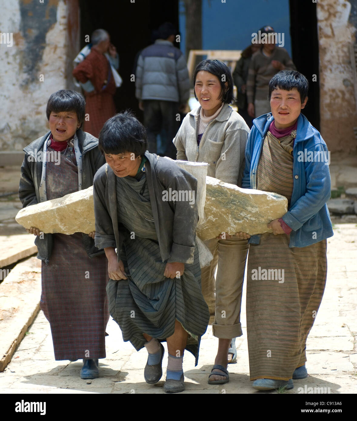 Freiwilligen Frauen kämpfen, um einen Block aus Stein für das renovierte Gangtey Gonpa Kloster im Phobjika Valley, Bhutan zu tragen. Stockfoto