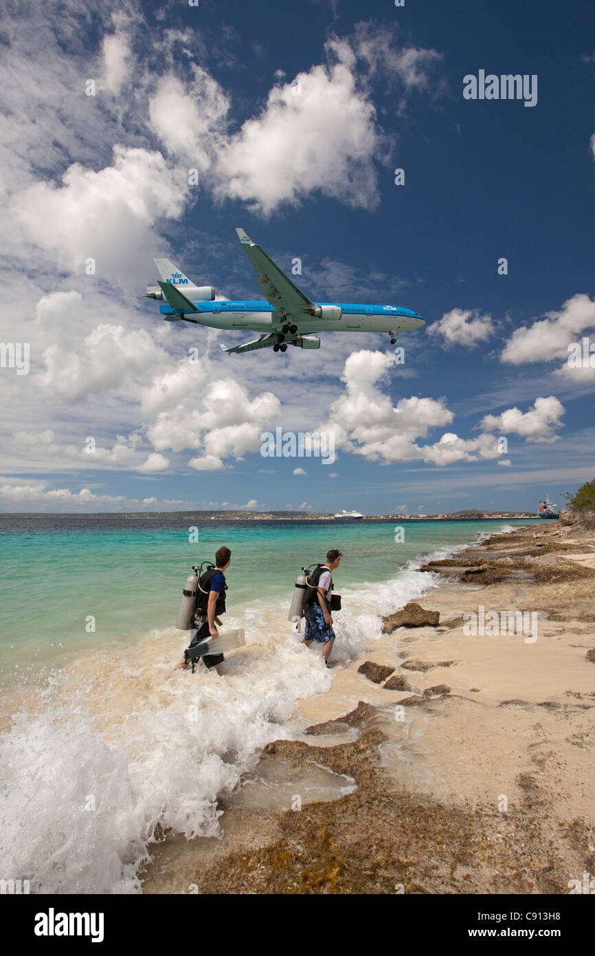Insel Bonaire, Niederländische Karibik, Kralendijk, KLM Douglas DC-10 Flugzeug Landung. Zwei Taucher aus dem Wasser kommen. Stockfoto