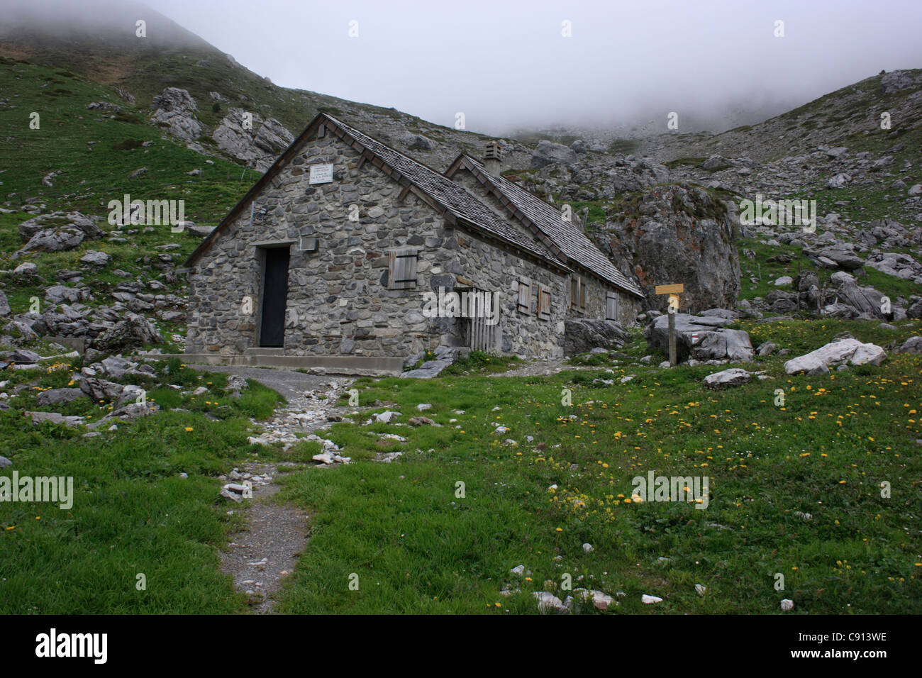 Es gibt kleine Berghütten für Kletterer auf dem Pic D'Anie und die Berge der Pyrenäen sind oft in Nebel gehüllt. Stockfoto