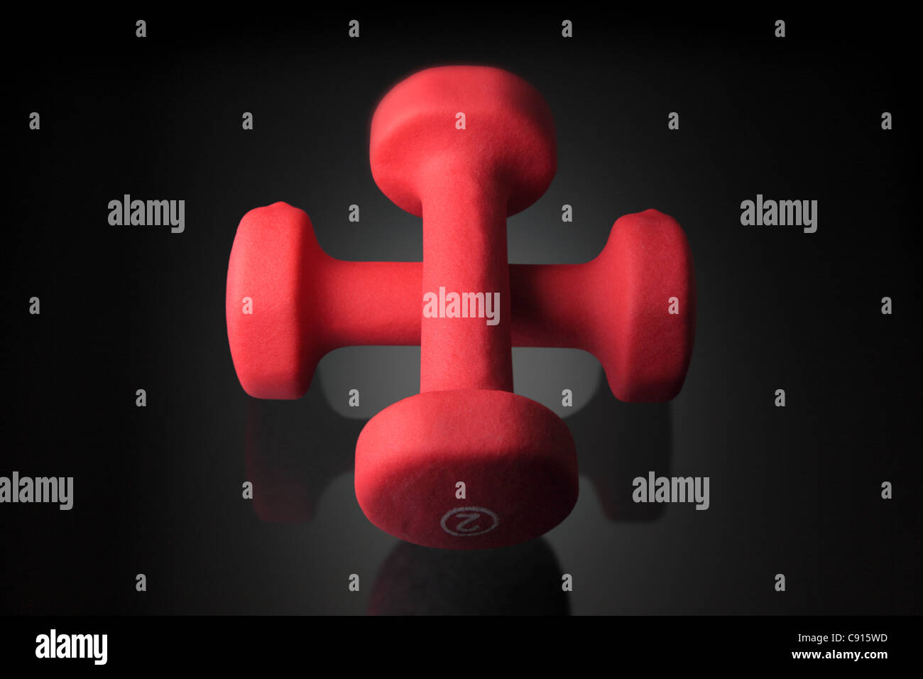 zwei Hand Gewichte auf einer dunklen reflektierenden Oberfläche in ein Kreuz angeordnet. Niedrigen Schlüssel kopieren-Raum. Stockfoto