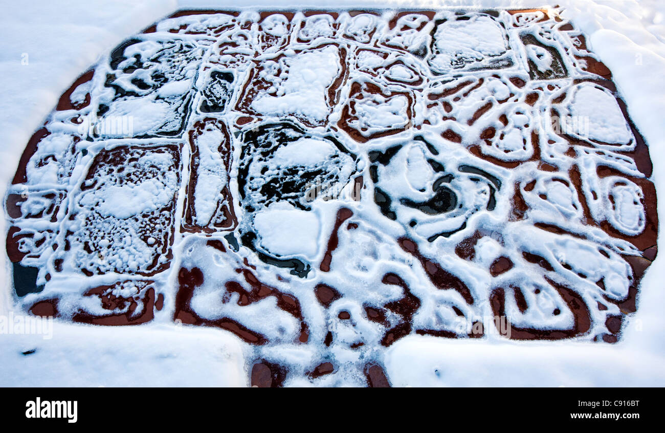 Schmelzender Schnee hinterlässt ein interessantes Muster auf eine Steinplatte Terrasse Stockfoto