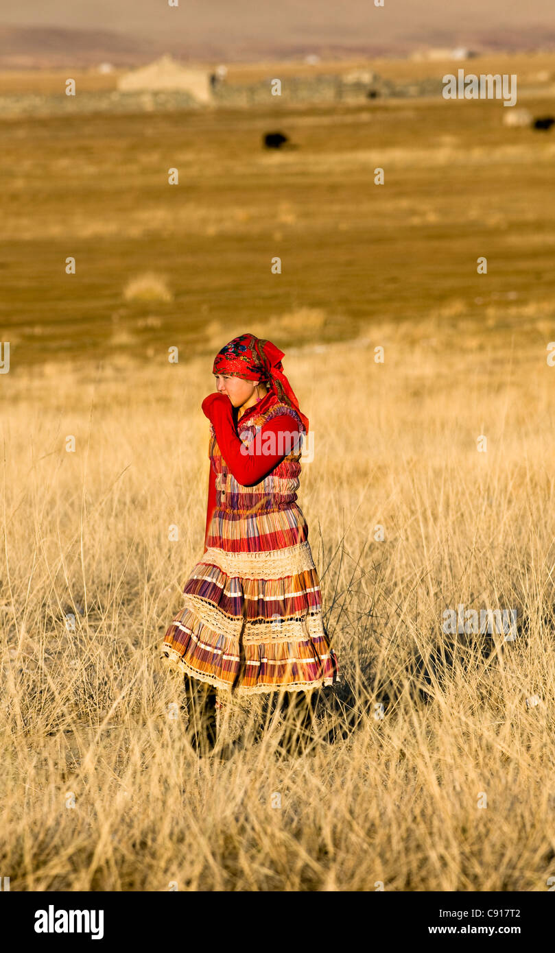 Eine kasachische Mädchen gekleidet in traditionellen kasachischen Kleidung zu Fuß durch das Grasland. Stockfoto
