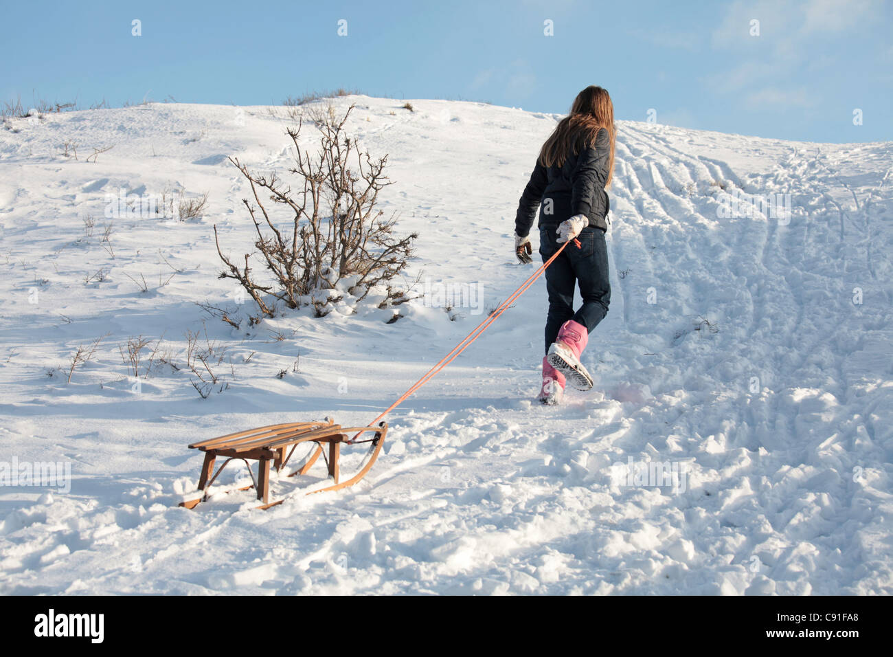 Eine Mädchen spielt mit ihren Schlitten im Schnee Stockfoto