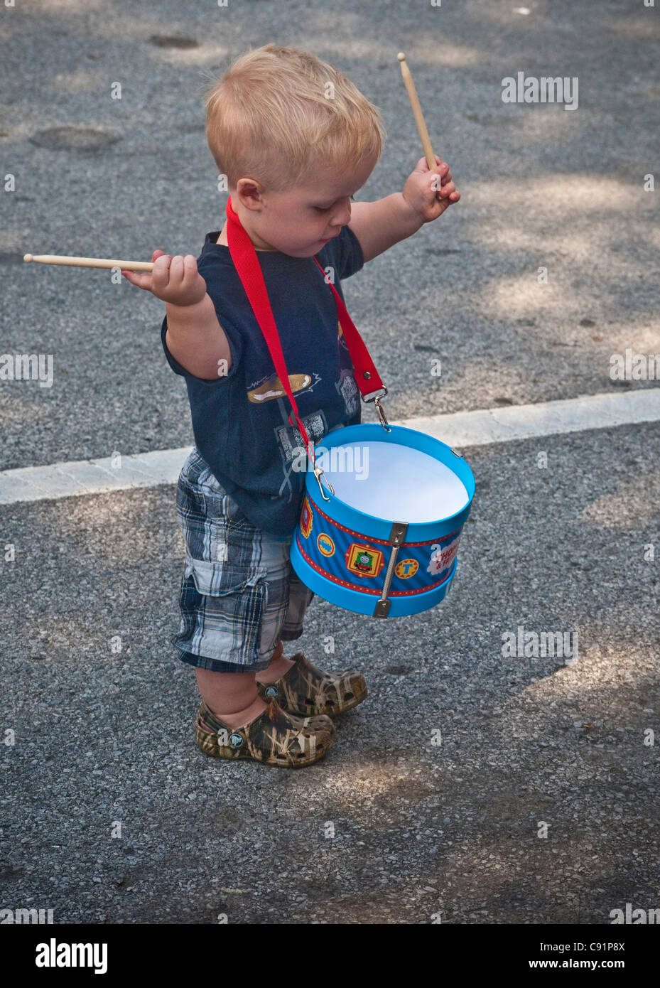 Kleine Stadt, Vorstadt, Patriotische Feiertage Parade. Kleiner Junge mit Spielzeug Trommel. Stockfoto