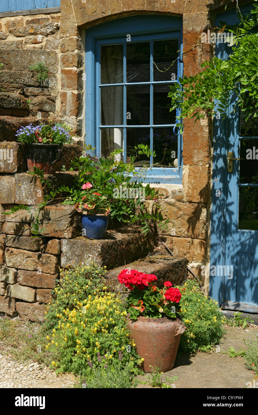 Schritte mit Blumentöpfe Dekoration außerhalb des hübschen Cotswold Cottage, Swerford Oxfordshire, England Stockfoto