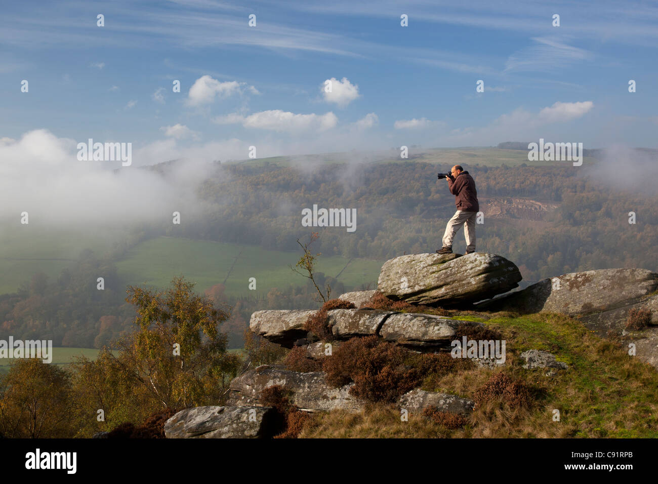 Fotograf auf Felsen am Froggett Rande Steilstufe mit Blick auf das Derwent Valley nahe Curbar, Peak District in Derbyshire, England Stockfoto