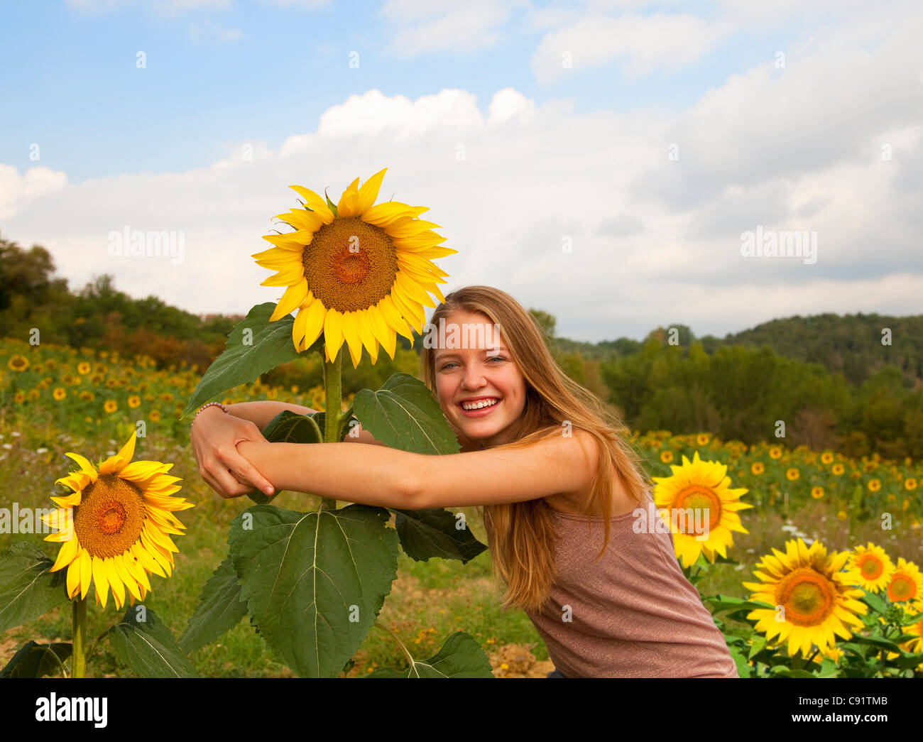 Teenager-Mädchen umarmt Sonnenblumen im Feld Stockfoto