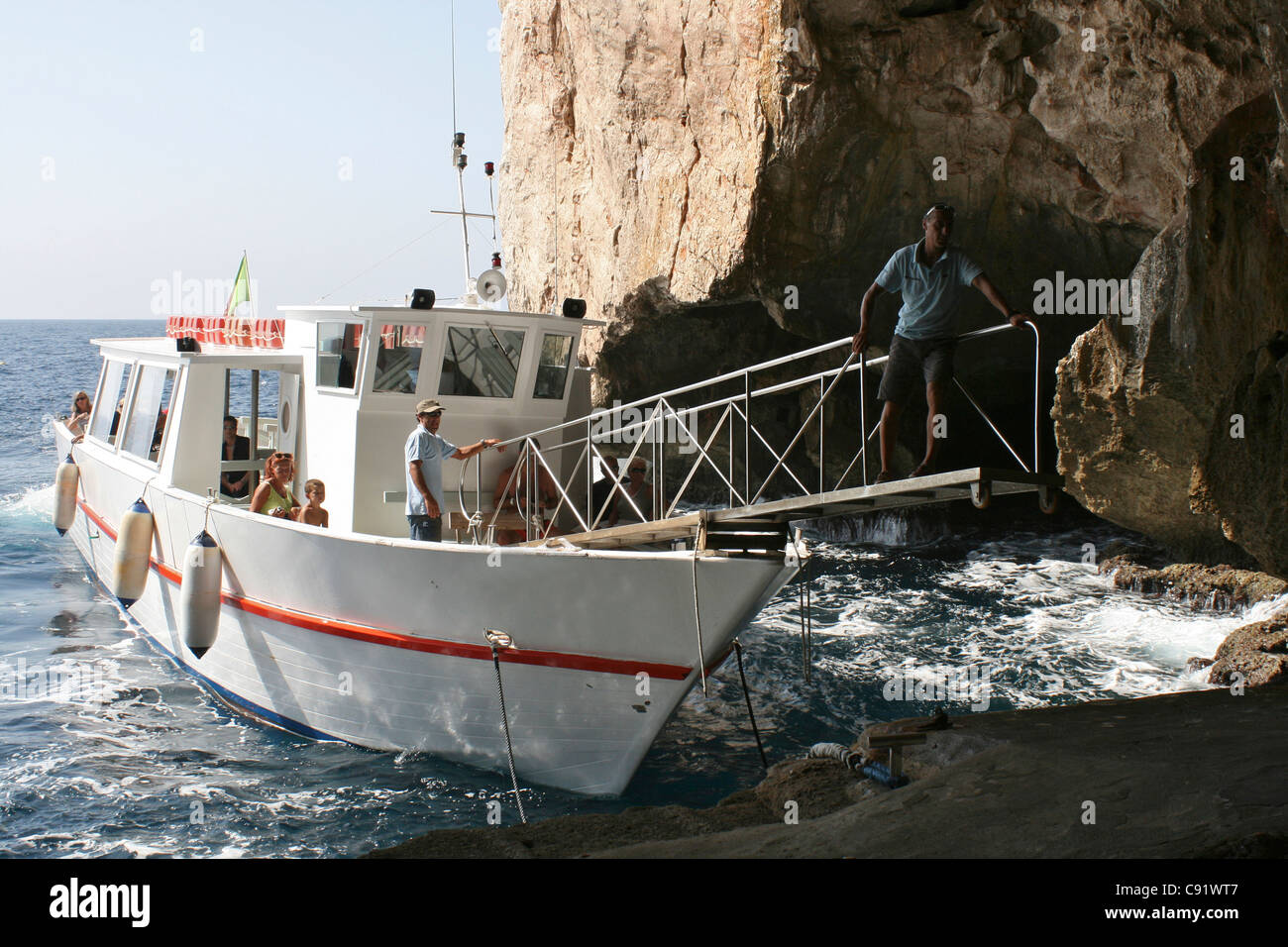 Touristenboot versucht, tie-up ermöglicht Touristen an Bord am Meeresspiegel Eingang zu Neptuns Grotte Grotta di Nettuno auf Stockfoto