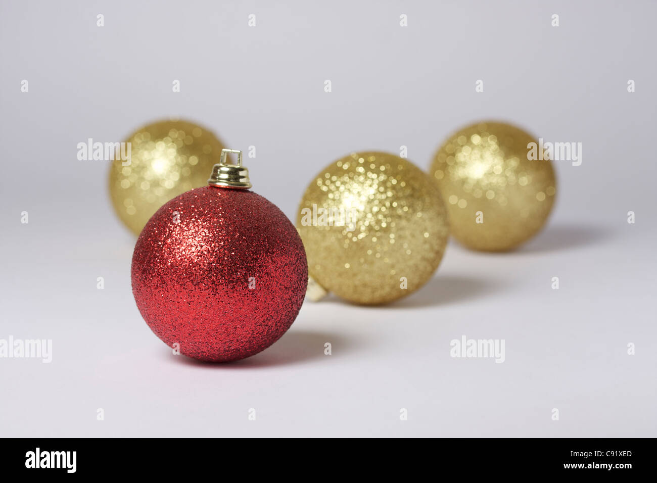 Vier Weihnachtskugeln. Konzentrieren Sie sich auf rot gefärbten Christbaumkugel in Vordergrund. Drei farbige Golddekorationen im Hintergrund Stockfoto