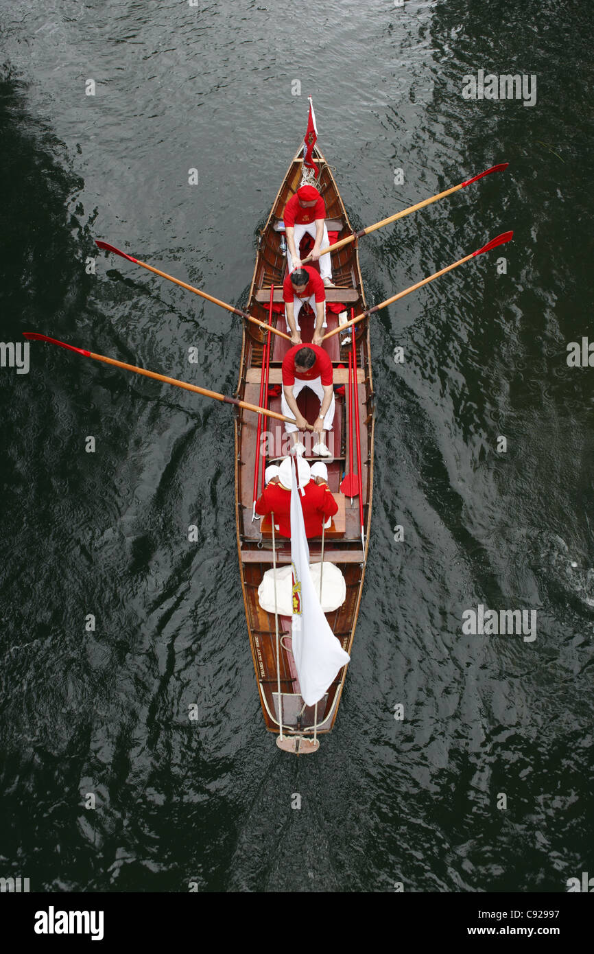 Swan-Oberteil in ihren traditionellen scarlet einheitliche Zeile Skiffs den Fluss hinunter, während Swan Upping, Themse, Henley, England Stockfoto