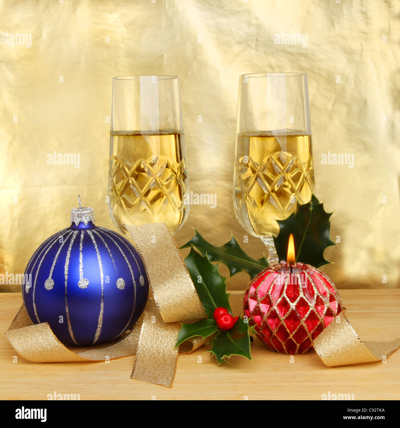 Weihnachten unter dem Motto Stillleben Champagner Gläser Dekorationen und eine dekorative Kerze auf einem goldenen Hintergrund Stockfoto