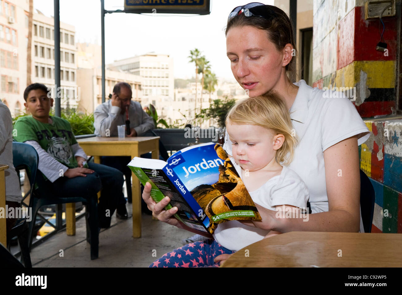Frau touristischen liest dem Lonely Planet-Reiseführer nach Jordanien im jordanischen Street Café beim Kleinkind Baby Tochter hielt. Amman Stockfoto