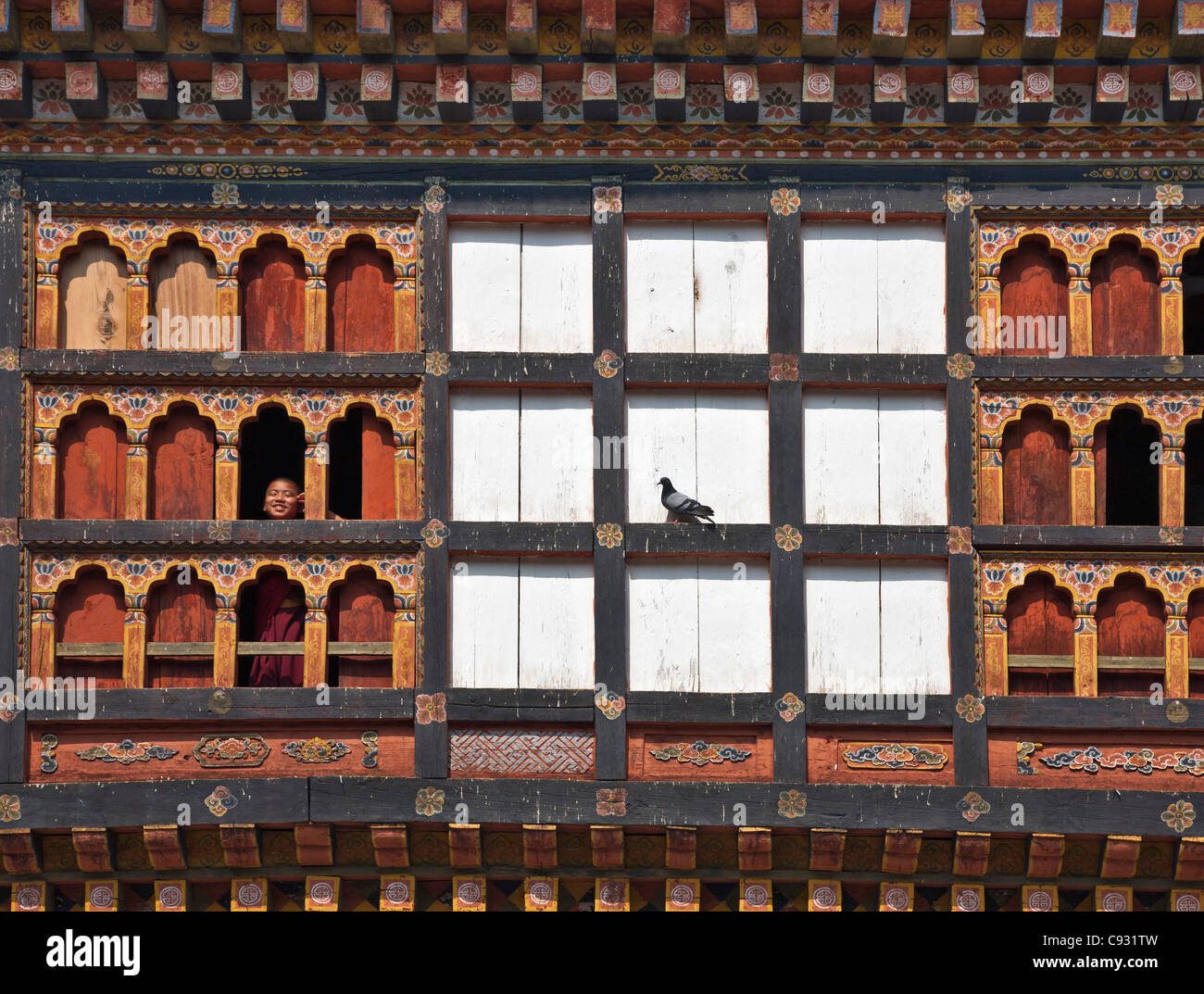 Ein junger Novize schaut die beeindruckende Dzong oder Festung am Trashigang aus einem shuttered Fenster. Stockfoto