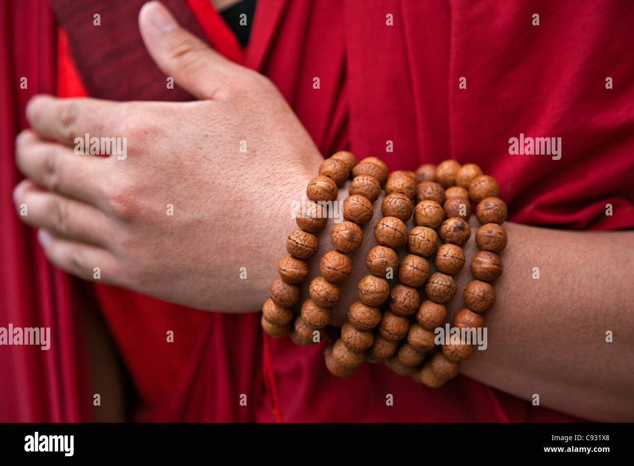 Gebetskette gewickelt runden das Handgelenk eines rot gekleideten Mönchs in der Nähe von Mongar. Stockfoto