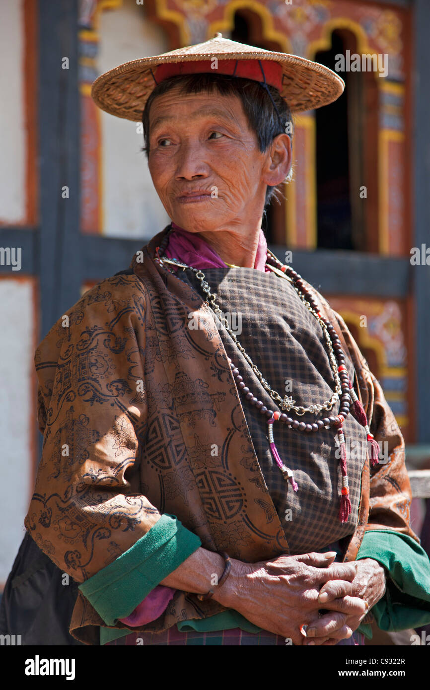 Eine bhutanische Frau in Tracht trägt einen traditionellen Bambushut Belo genannt. Stockfoto